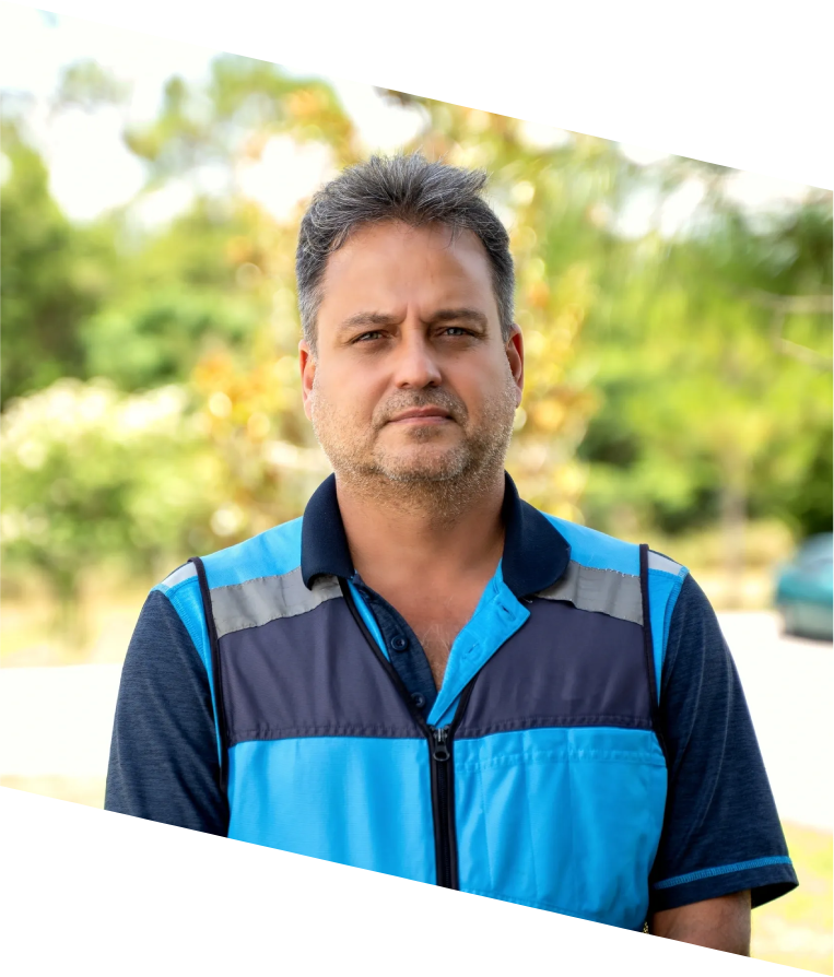 A man in blue and black shirt standing next to trees.