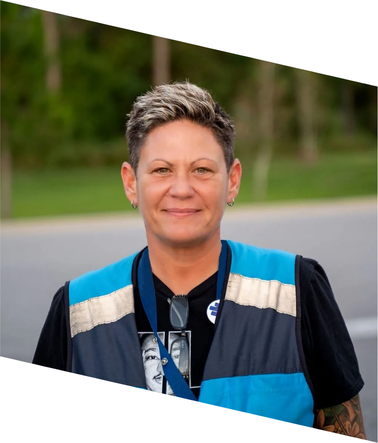 A woman with short hair wearing a blue vest.